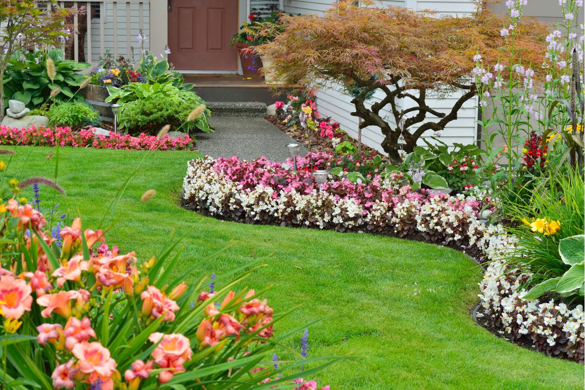 A well-maintained garden with a variety of colorful flowers, a neatly trimmed lawn, and a pathway leading to a red door offers inspiring home exterior ideas.