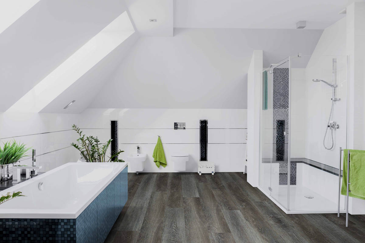 A modern bathroom in Marietta featuring a bathtub, glass shower, two sinks, and a sloped ceiling. The room includes green towels and plants, complemented by dark wood flooring and pristine white walls.