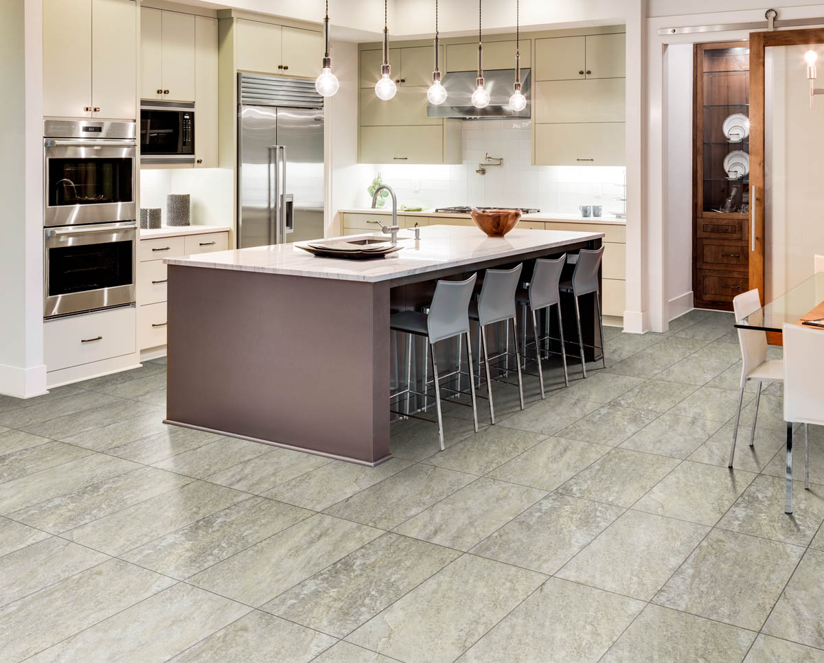 A modern kitchen with white cabinetry, stainless steel appliances, an island with bar stools, pendant lights, and expertly done flooring installation.