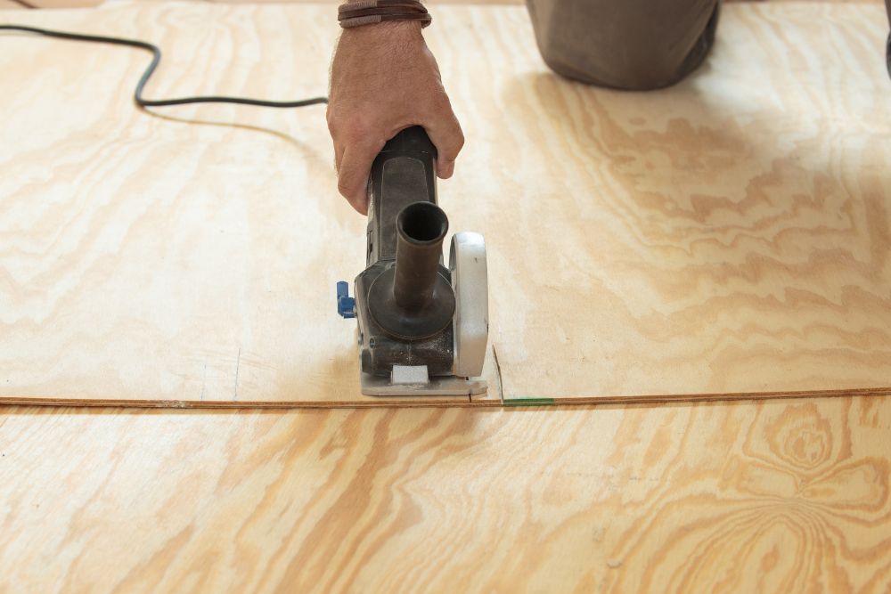 A person is using a circular saw to cut a piece of plywood, demonstrating the precision needed for about any DIY project.