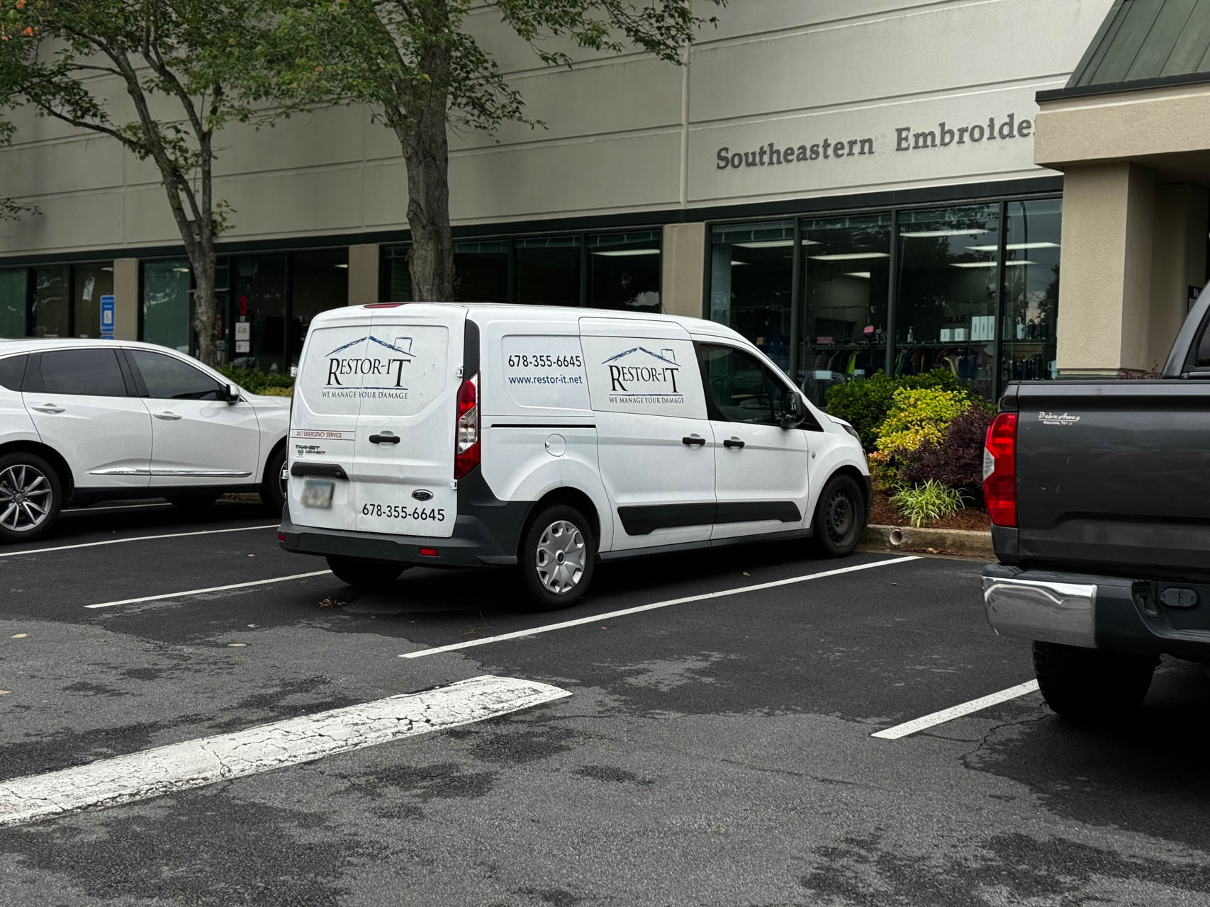 A white van with the "Restore-It" logo and contact information is parked in front of their Marietta office location. About it, other vehicles are also visible.