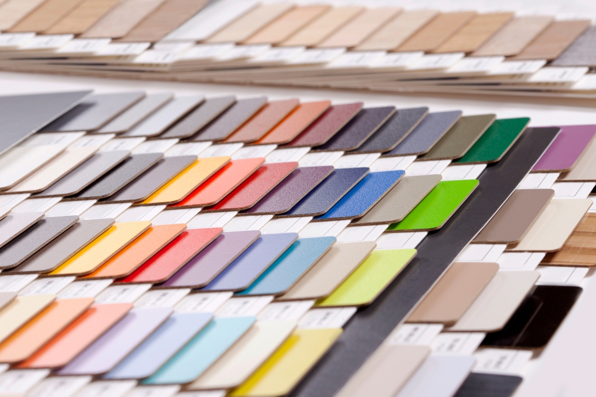 An array of color swatches displayed, showcasing a wide range of colors including shades of red, blue, green, yellow, and neutrals. The organized rows present a cohesive look similar to glue down vinyl plank flooring.